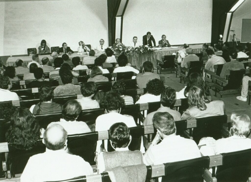 Foto em preto e branco dos participantes e platéia sentados no auditório durante o seminário.